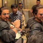 Catch Shah Rukh Khan's delightful airport rendezvous with fans as he flaunts a stylish ponytail, igniting social media buzz and admiration.